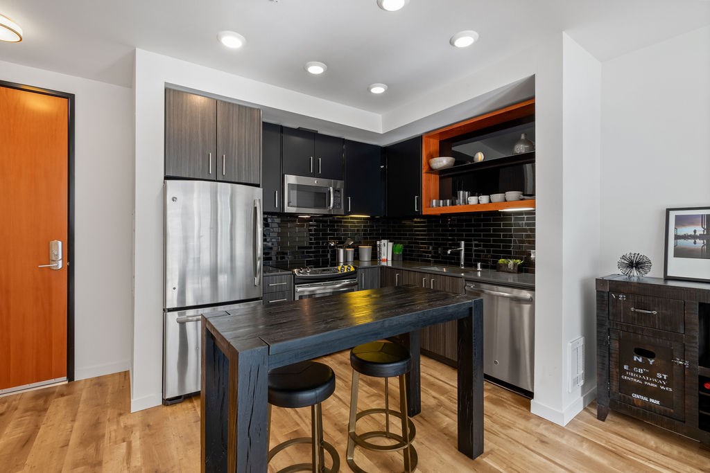 A modern kitchen with a black countertop and stainless steel appliances.
