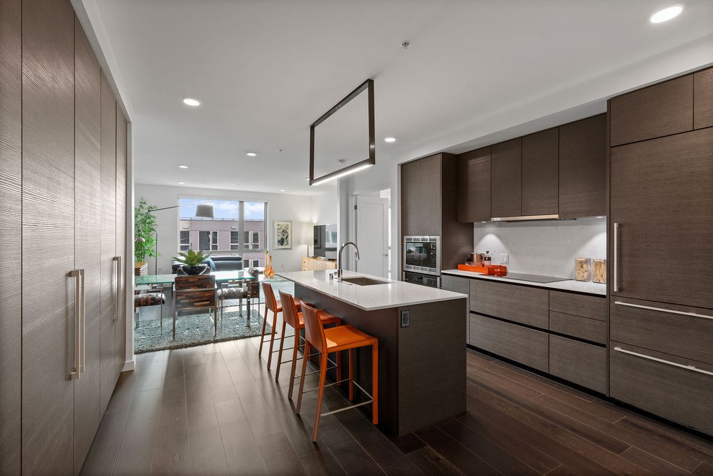 A modern kitchen with a large island and wooden floors.