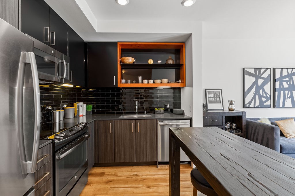 A modern kitchen with a wooden table and stainless steel appliances.