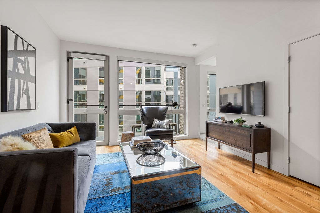 A living room with a grey couch and a blue rug.