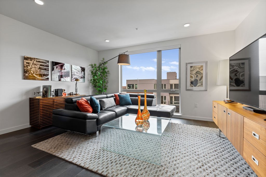 A modern living room with a black leather couch and a glass coffee table.