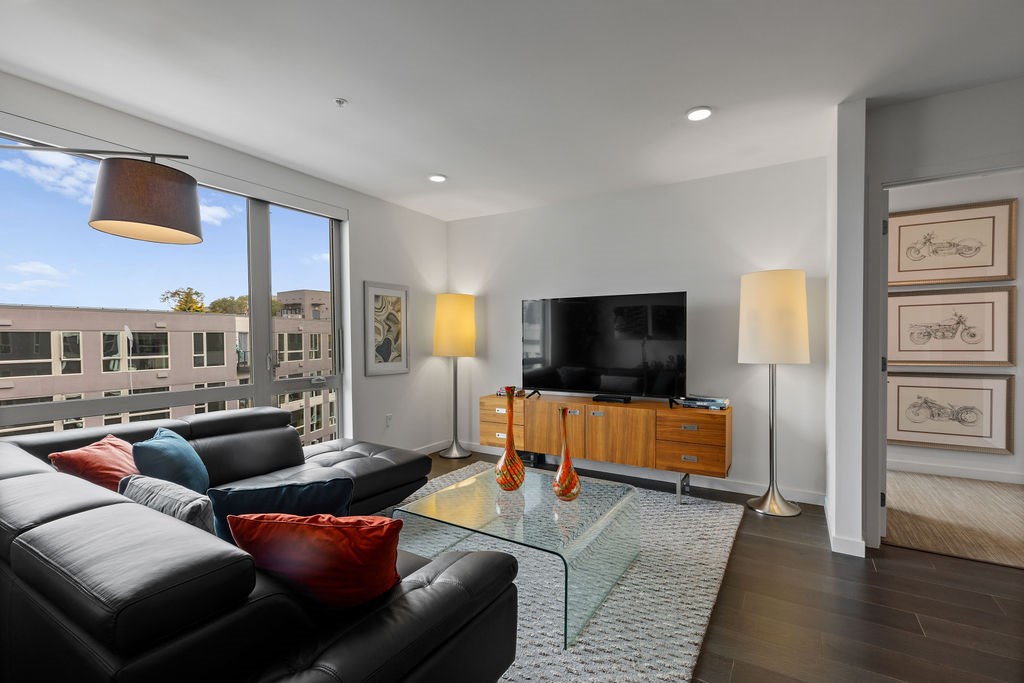 A living room with a black couch and a glass coffee table.