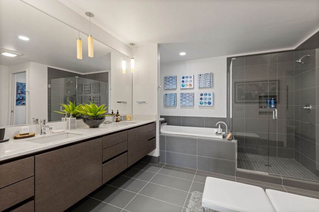 A modern bathroom with a large mirror and a white bathtub.