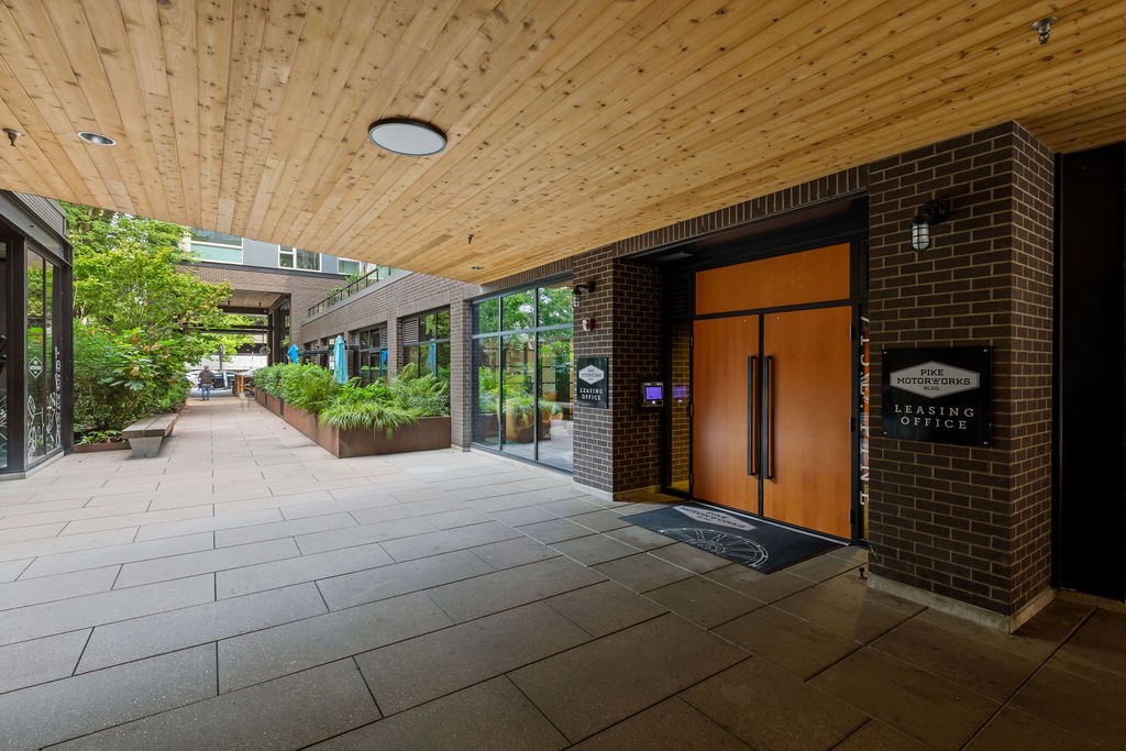 A wooden covered walkway leads to a building with a leasing office.