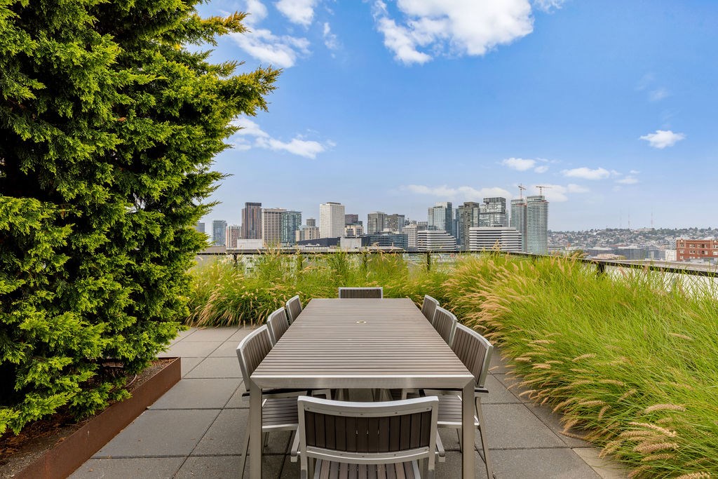 A table and chairs are set up on a patio with a city skyline in the background.