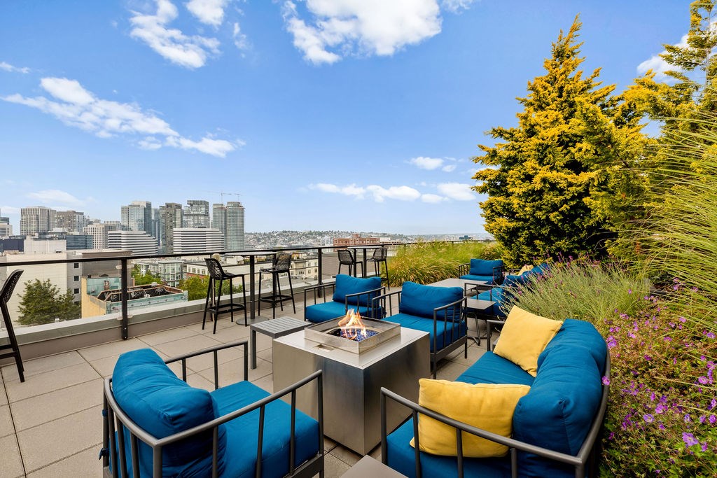A patio with blue chairs and a table with a view of the city.