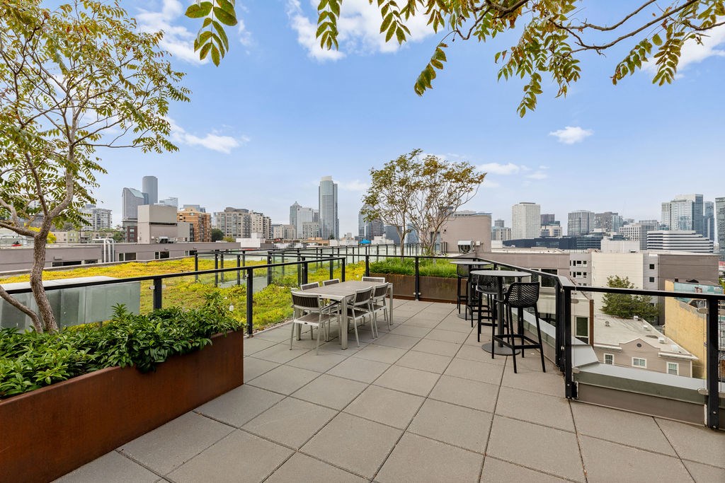 A patio with a table and chairs overlooking a city skyline.