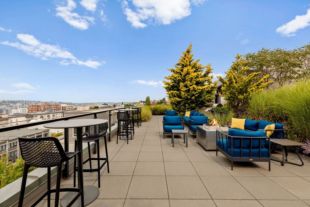 A patio with blue couches and a table with chairs overlooking a city.