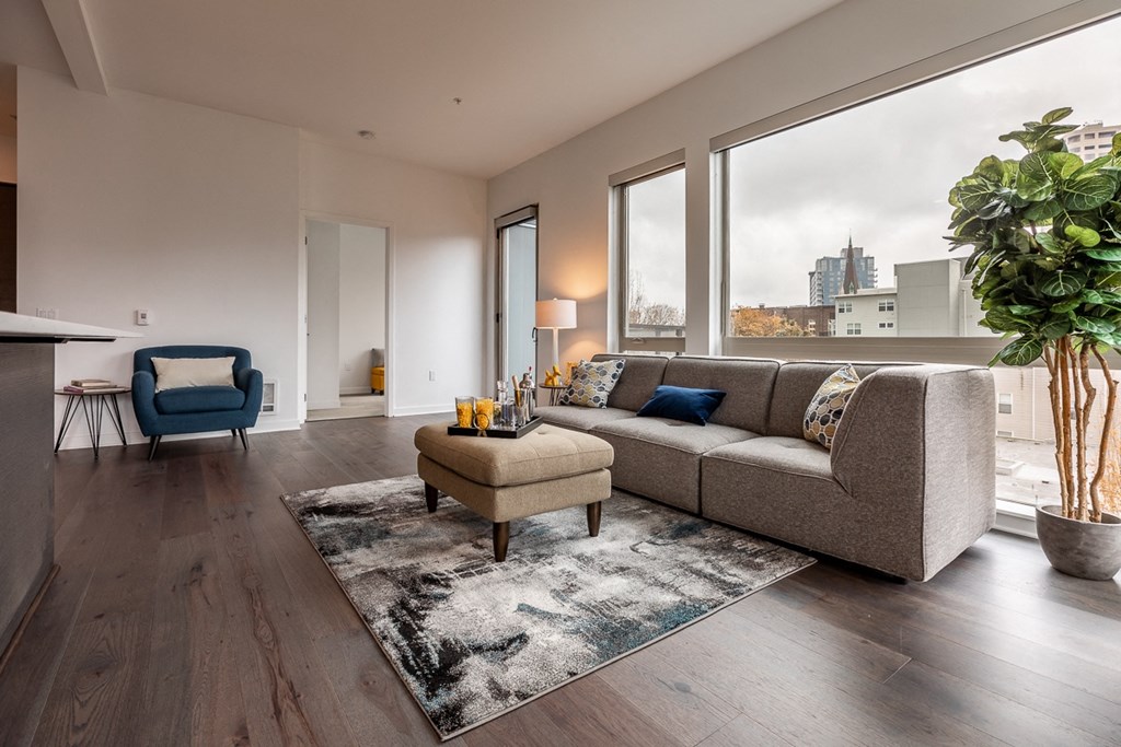 Window-Lit Lounge Area with Couch, Ottoman, and Decor Plant