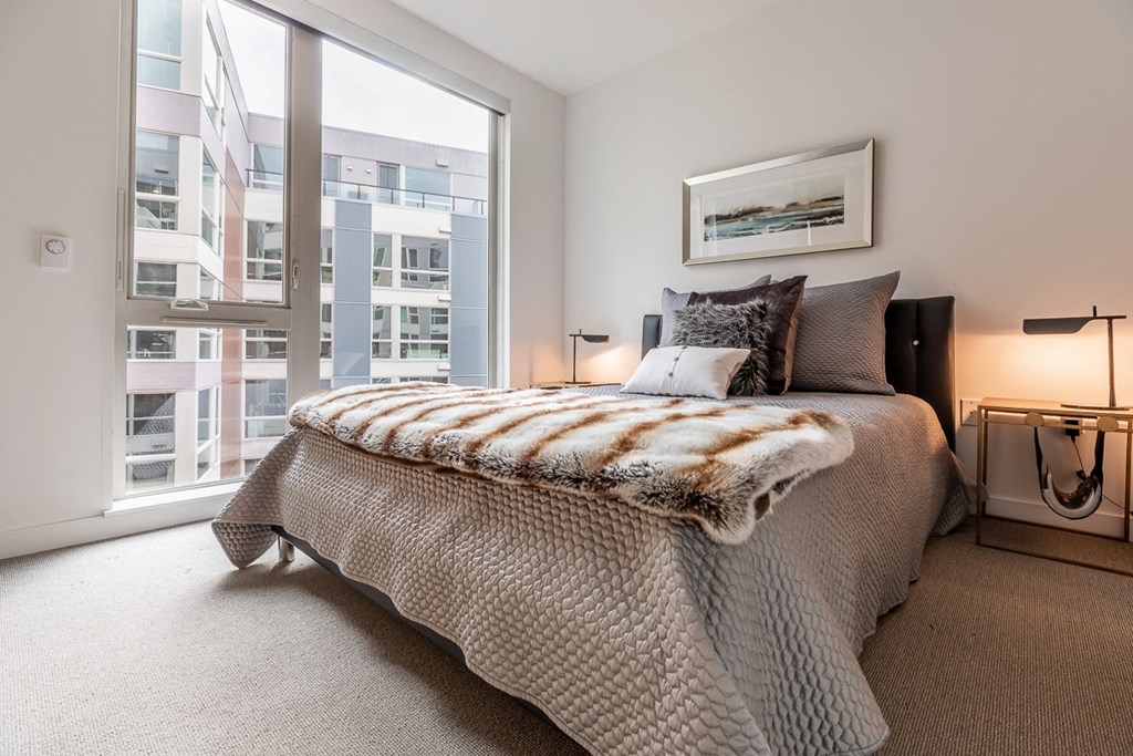 Bedroom with Floor-to-Ceiling Window and Framed Wall Art Above Bed