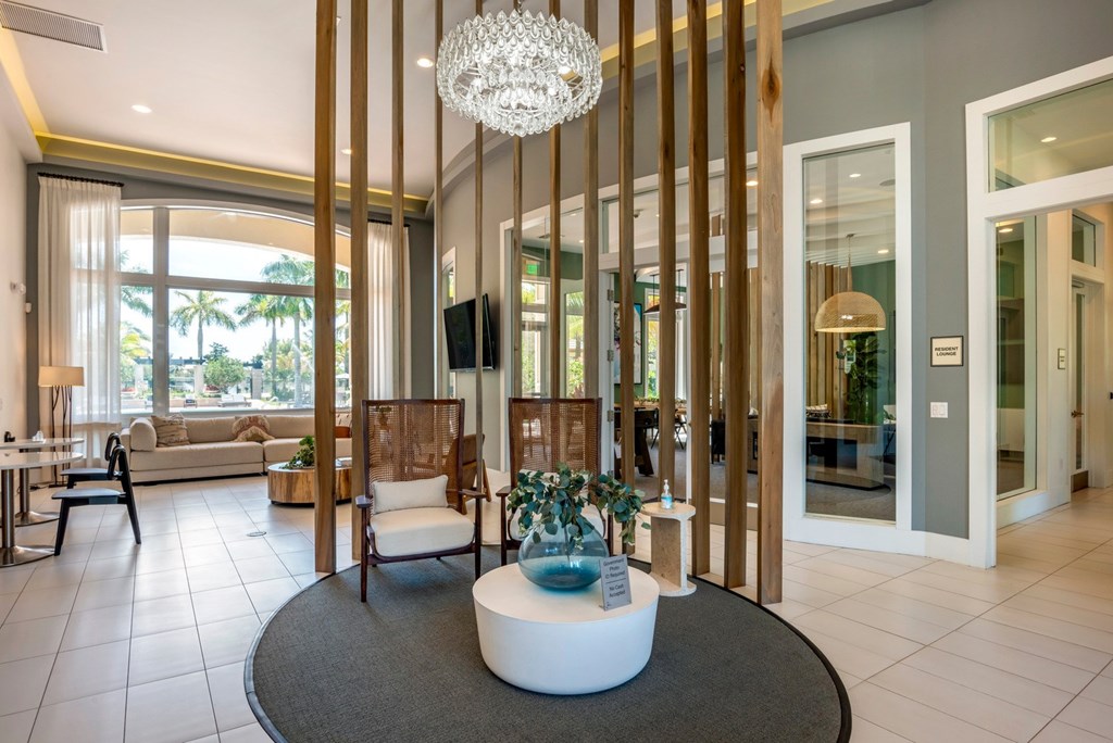 A modern living room with a large chandelier and a white circular coffee table.
