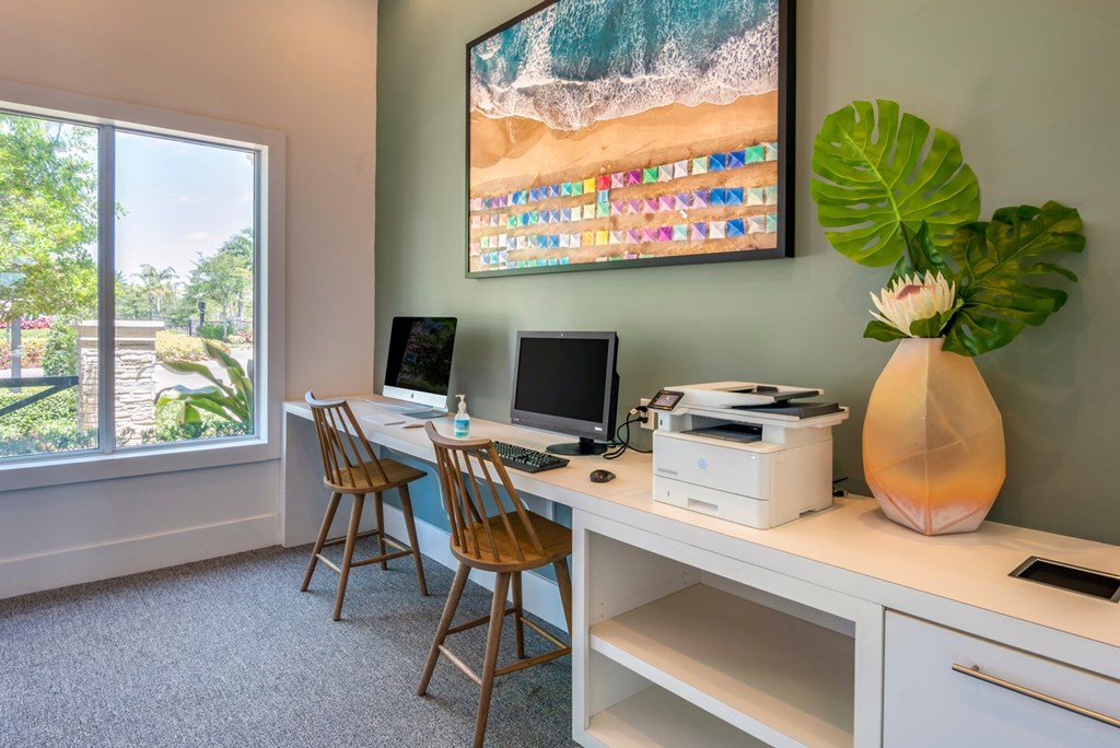 A room with a desk, chairs, and a large painting of a beach scene.