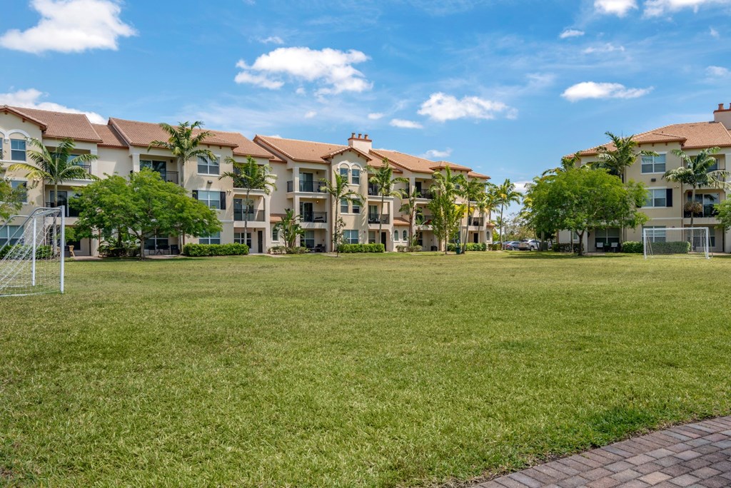 A grassy area in front of a row of apartment buildings.