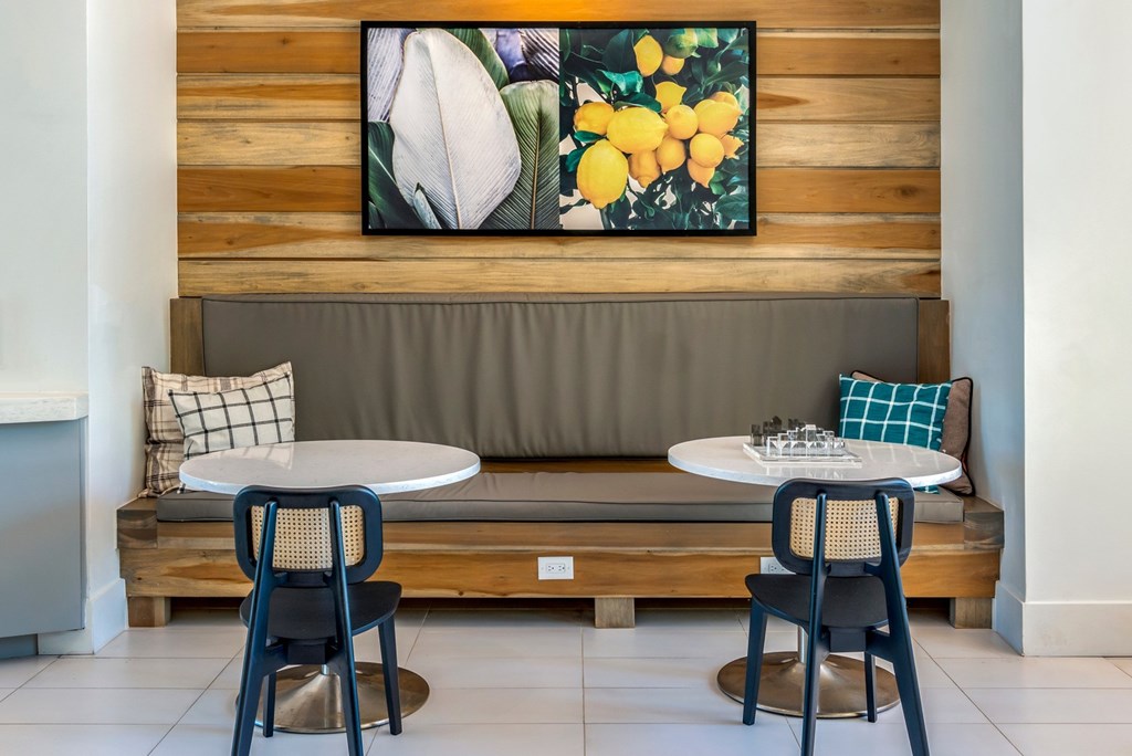 A wooden bench with a grey cushion and a painting of flowers above it.