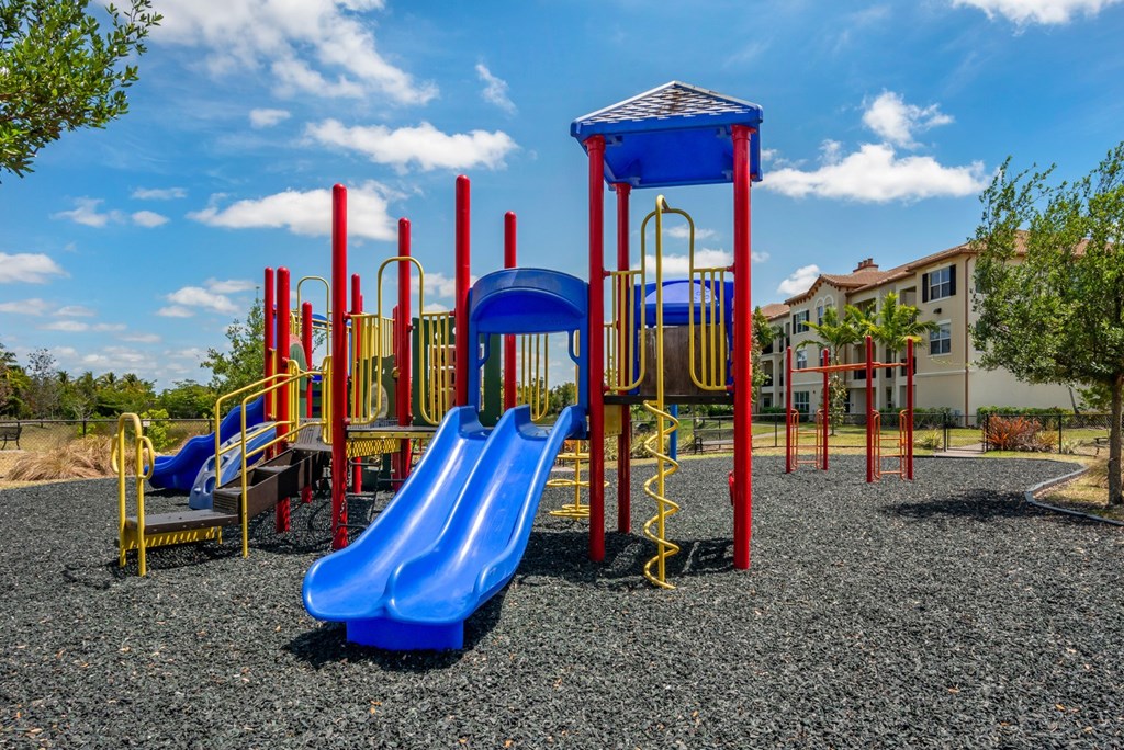 A playground with a blue slide and red and yellow play structures.