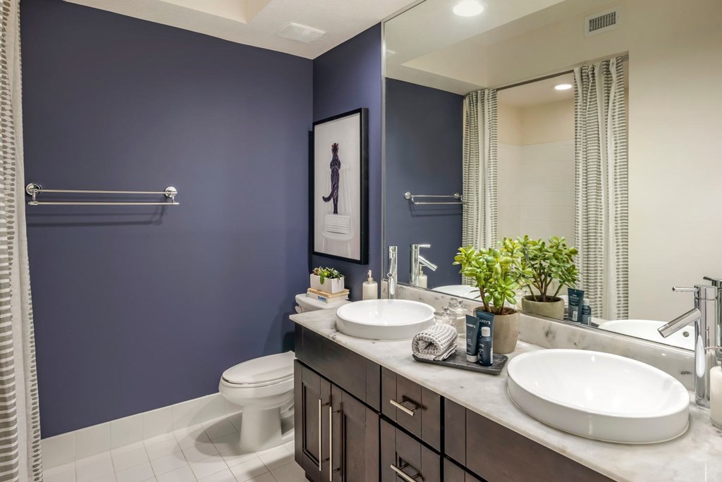 A bathroom with a toilet, sink, and mirror.