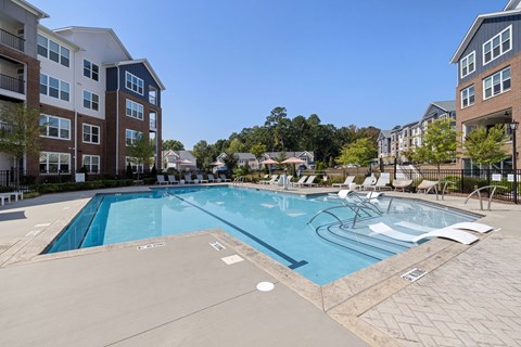 Resort-style pool at Alta Wren with a tanning ledge, in-water loungers, and a paver sundeck framed by the buildings.