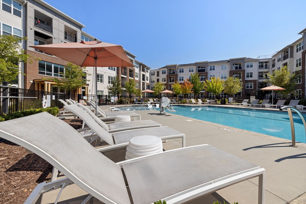 A sun lounger is in the foreground of a swimming pool.