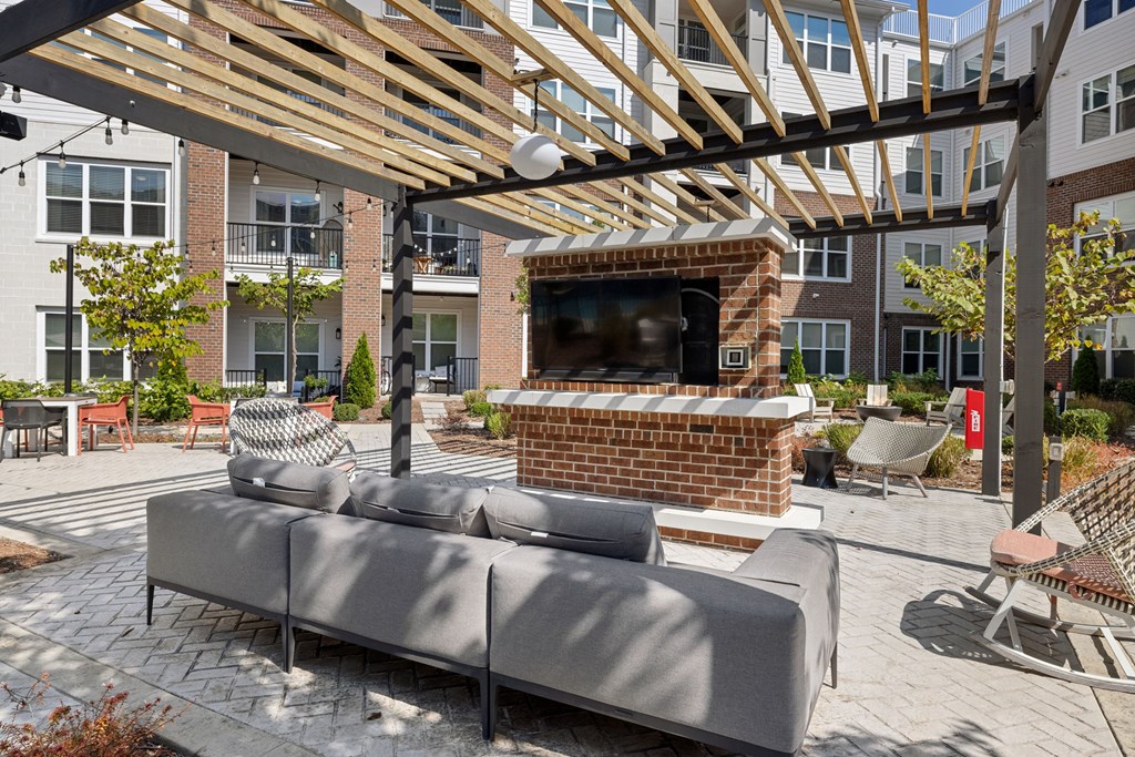 A patio with a couch and a television under a wooden roof.