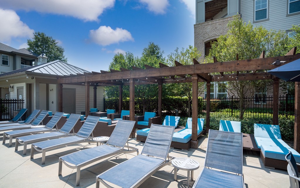 Outdoor Poolside Lounge Area Featuring Pergola, Sunbeds, and Umbrellas