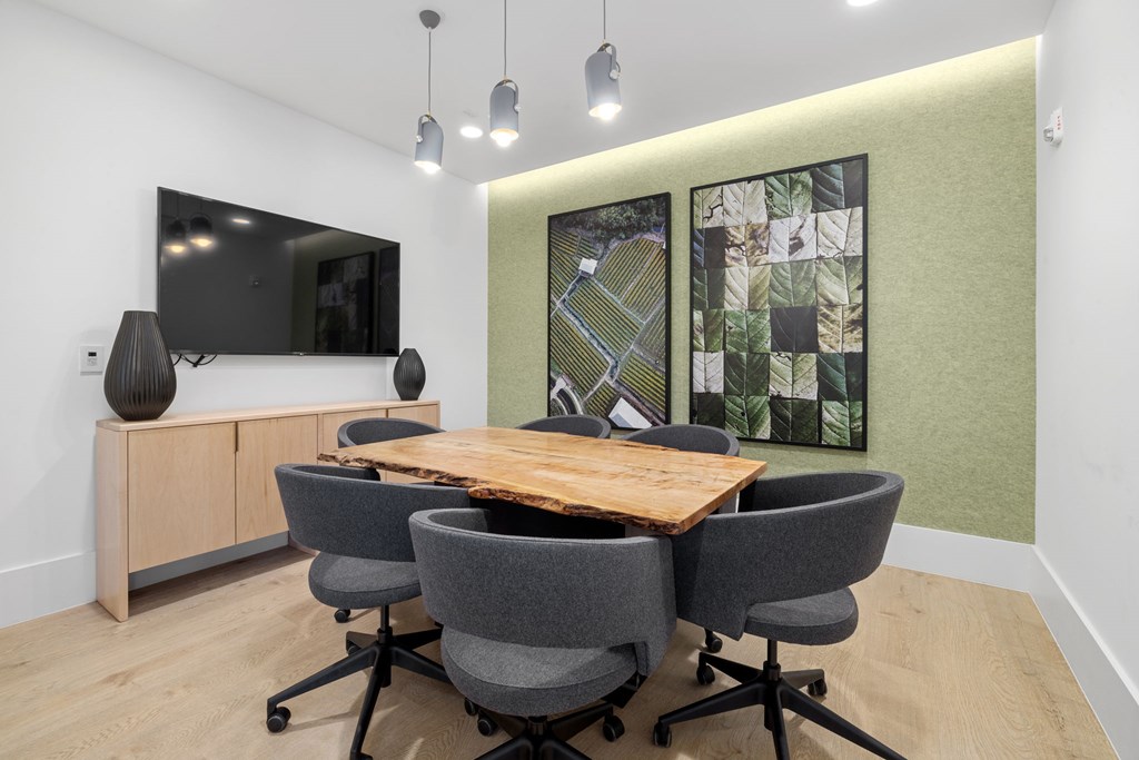 A conference room with a wooden table and grey chairs.