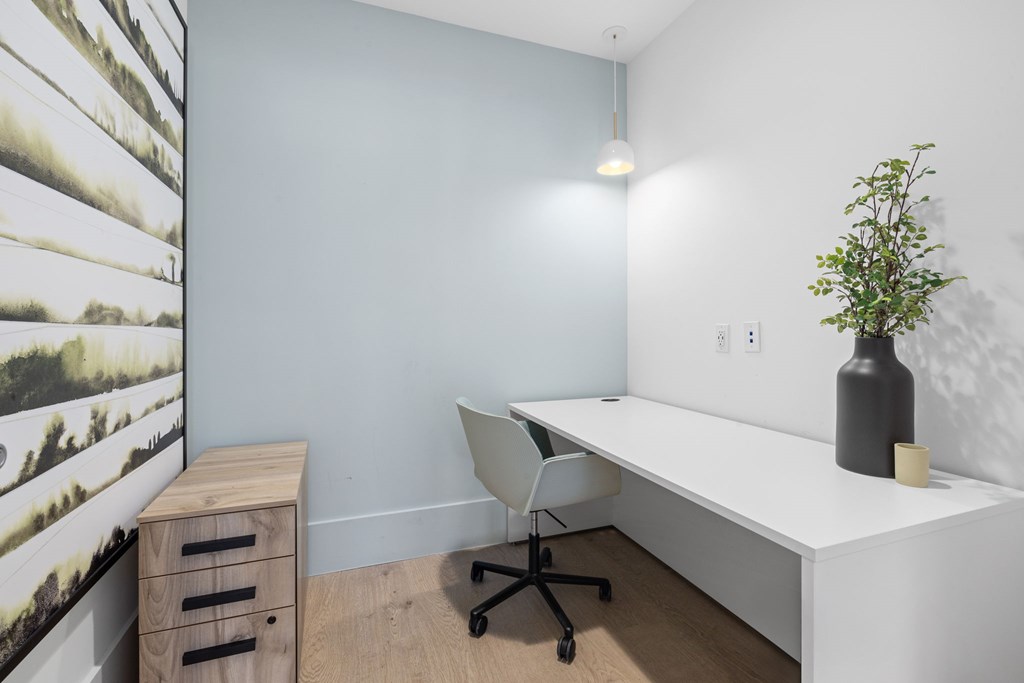 A white desk with a black vase and a plant on it.