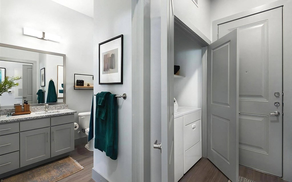 Entryway View Showing Bathroom with Granite Countertop and In-Unit Laundry Closet