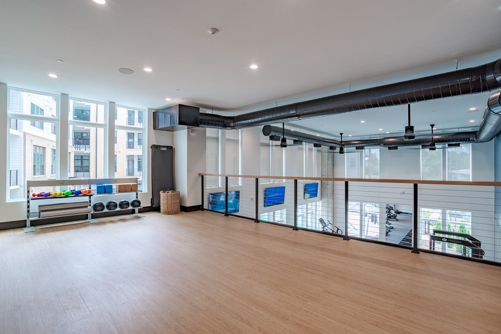 A spacious room with wooden floors and a balcony with a railing.