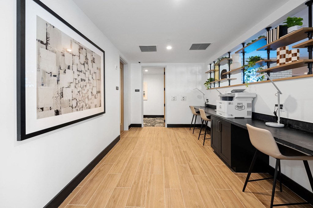 A long hallway with a framed picture on the wall and a white box on the counter.