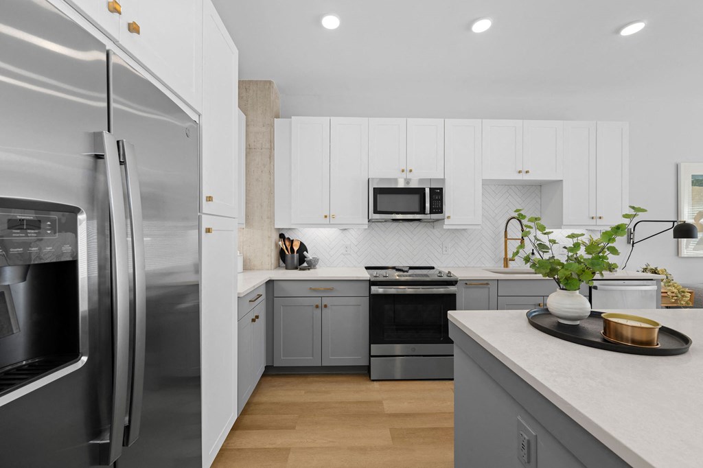 A modern kitchen with a stainless steel refrigerator and wooden flooring.