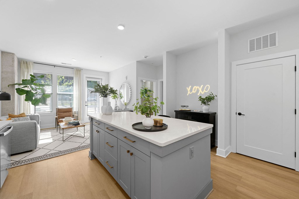 A kitchen with a large island and a dining area with chairs and a table.
