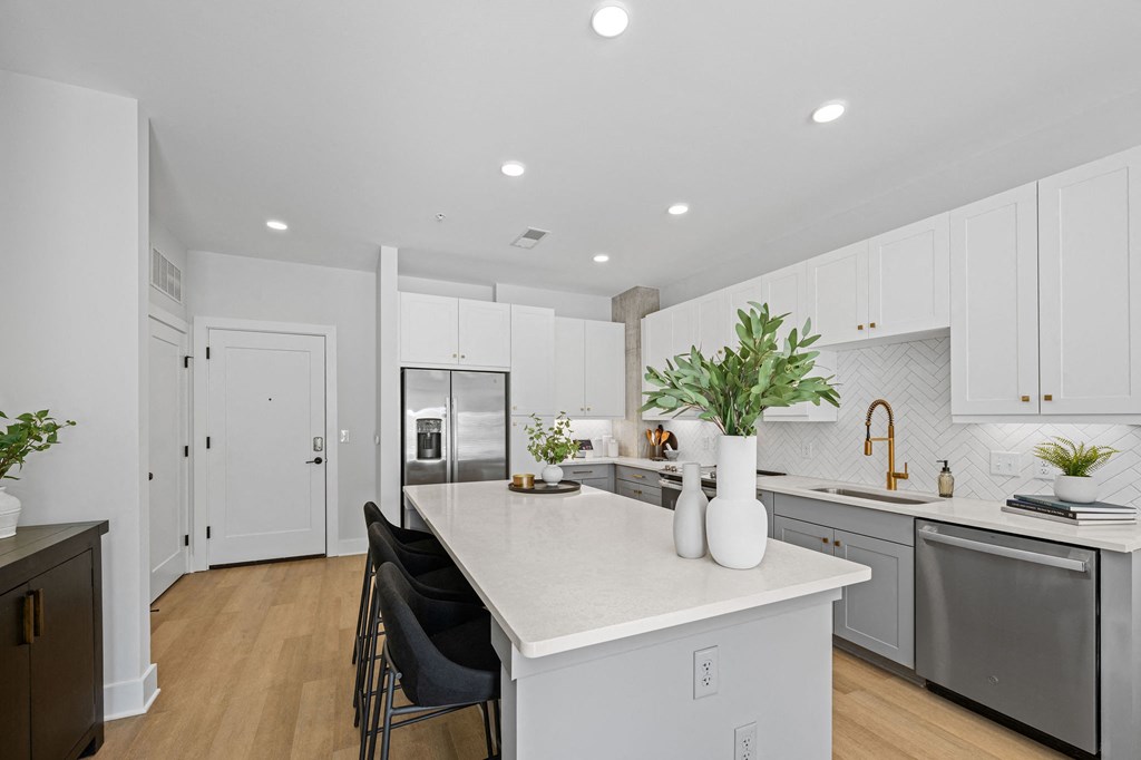 A kitchen with a white countertop and black chairs.