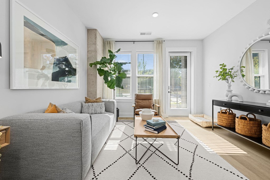 A living room with a grey couch, a coffee table, and a large mirror on the wall.
