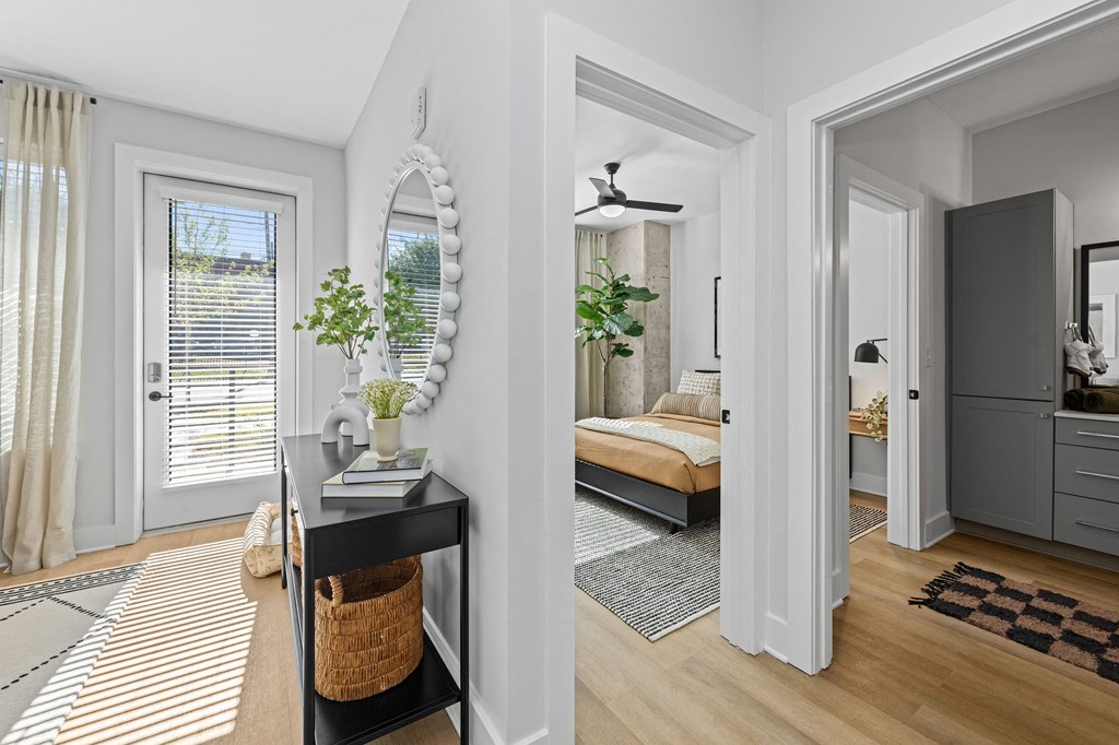 A room with a bed, a mirror, and a plant on a table.