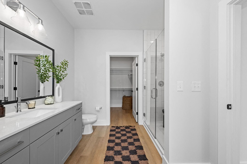 A bathroom with a checkered rug on the floor.