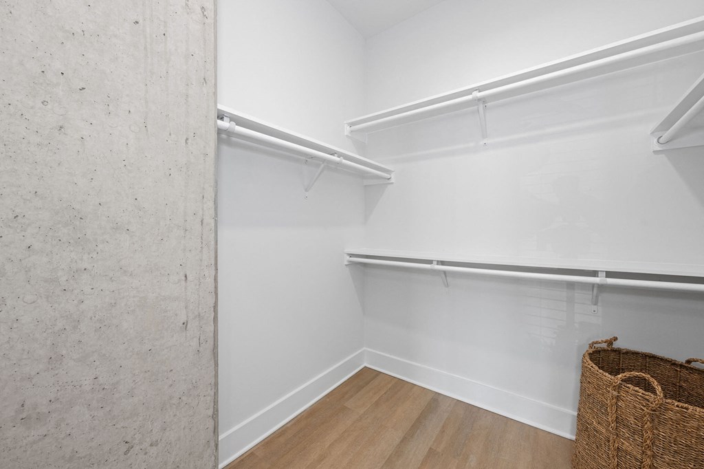 A room with a white wall and a wooden floor with a wicker basket on the floor.