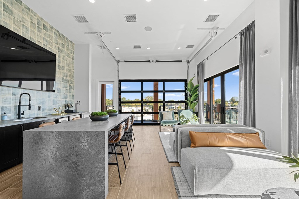 A modern kitchen with a large island and a dining area with a view of the outdoors.