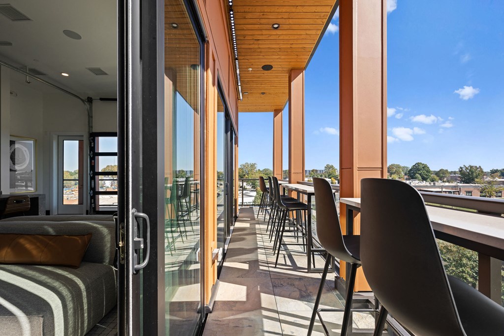 A balcony with chairs and a table is overlooking a city.