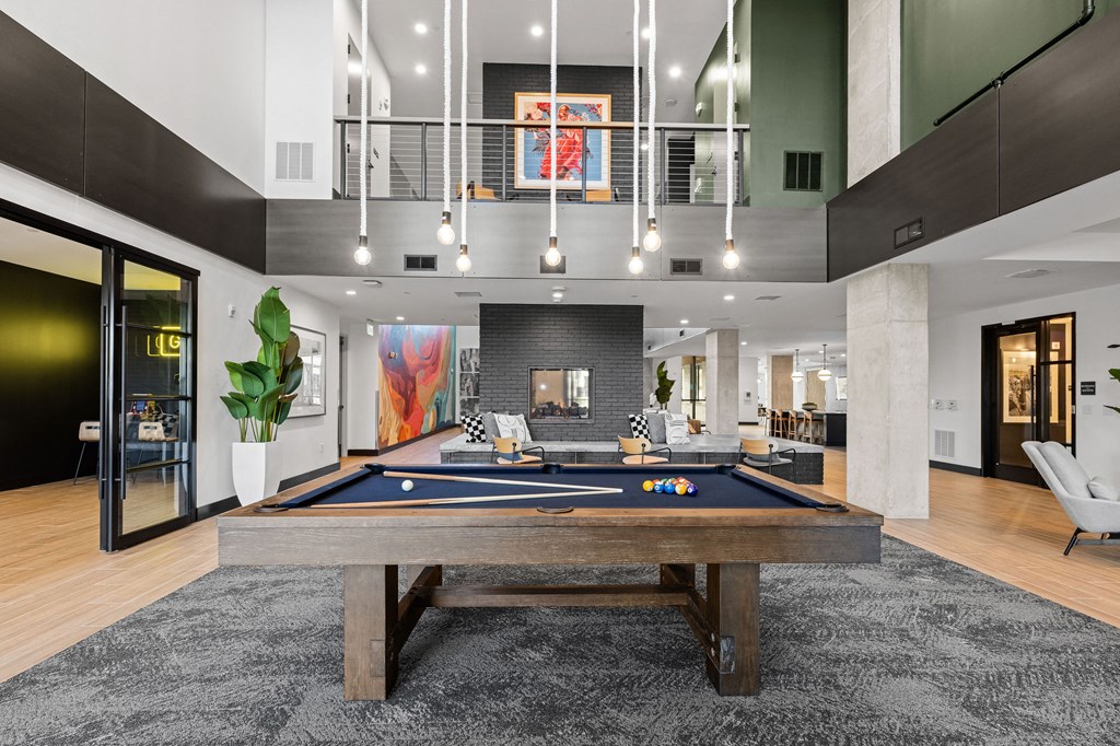 A pool table is in the middle of a room with a black carpet.