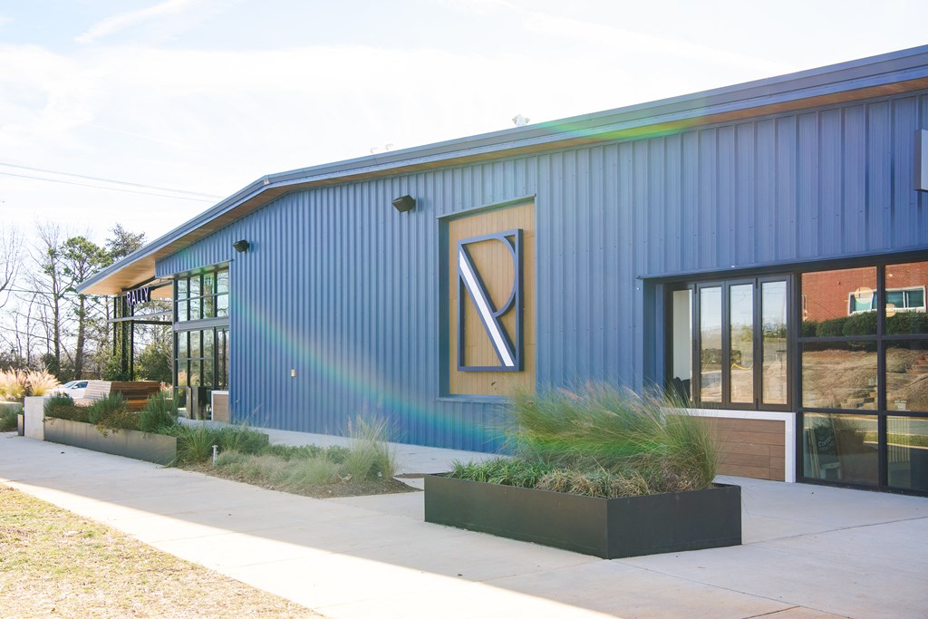 a blue building with a large window and a sidewalk with plants