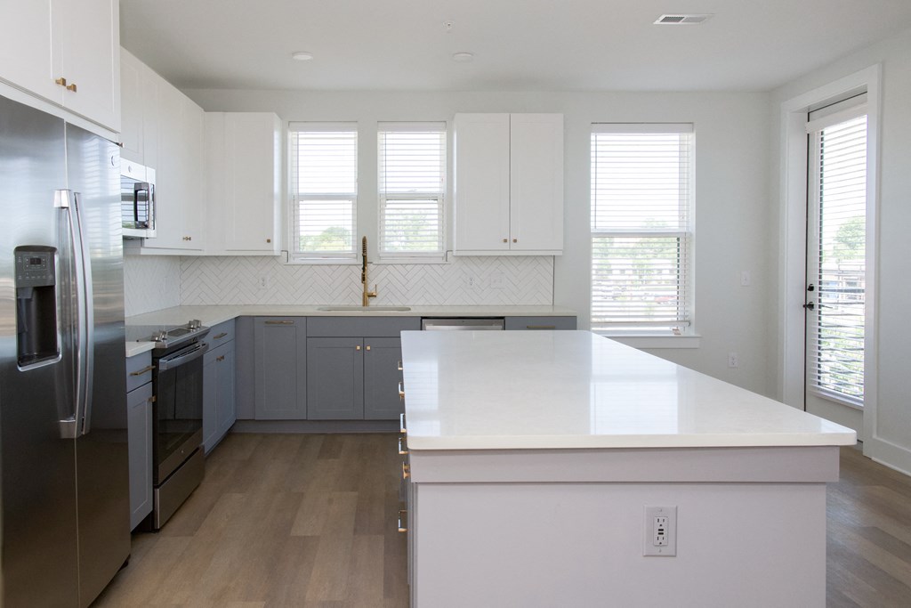 a large white kitchen with white counter top and stainless steel appliances