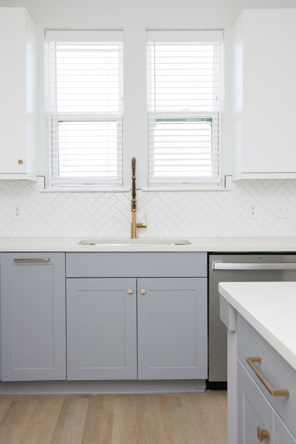a kitchen with white cabinets and a sink and two windows