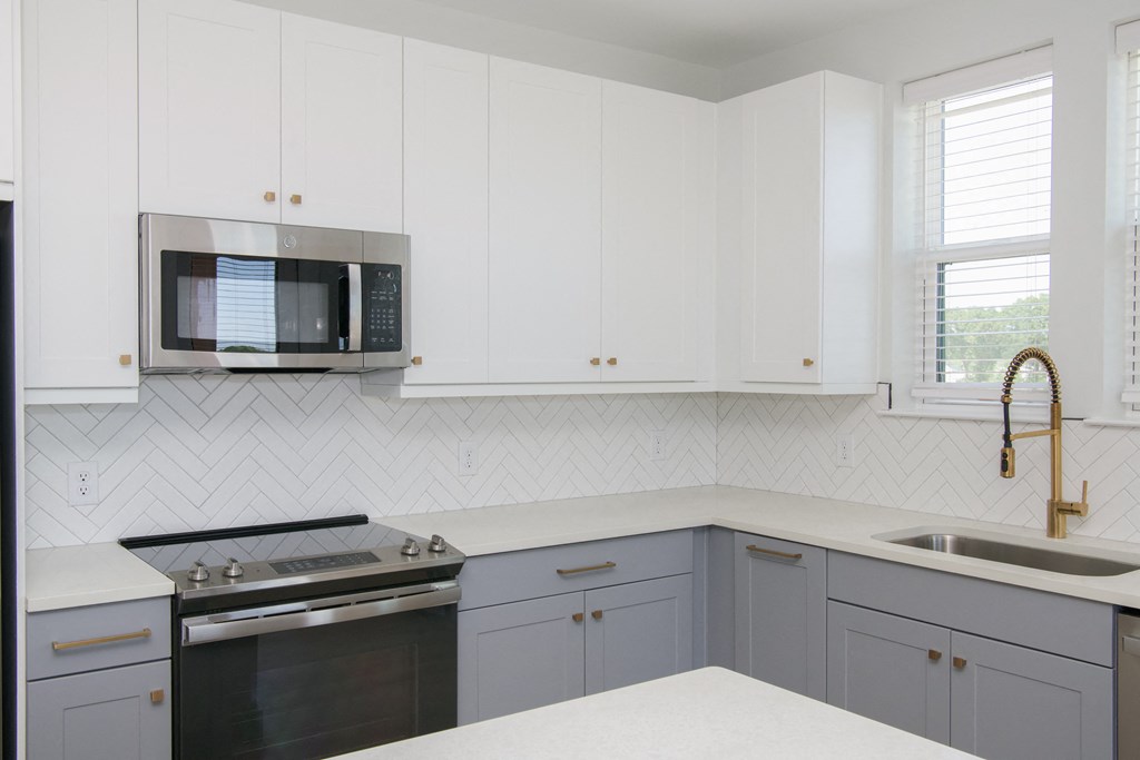a kitchen with white cabinets and a stove and a microwave