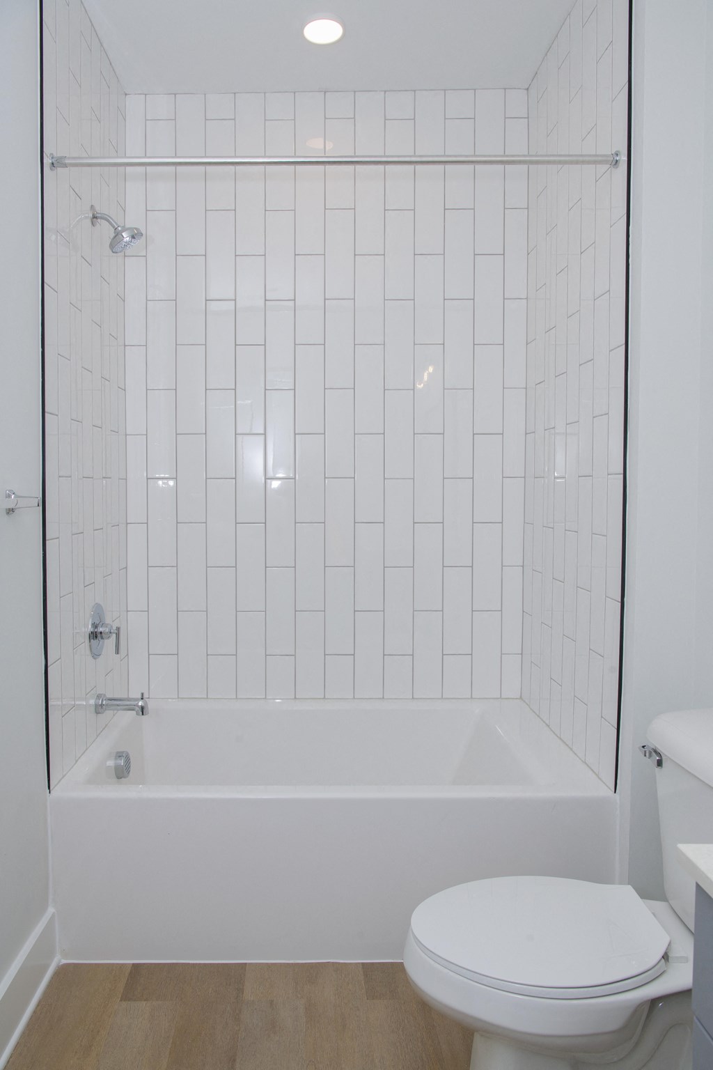 a white tiled bathroom with a shower and a toilet