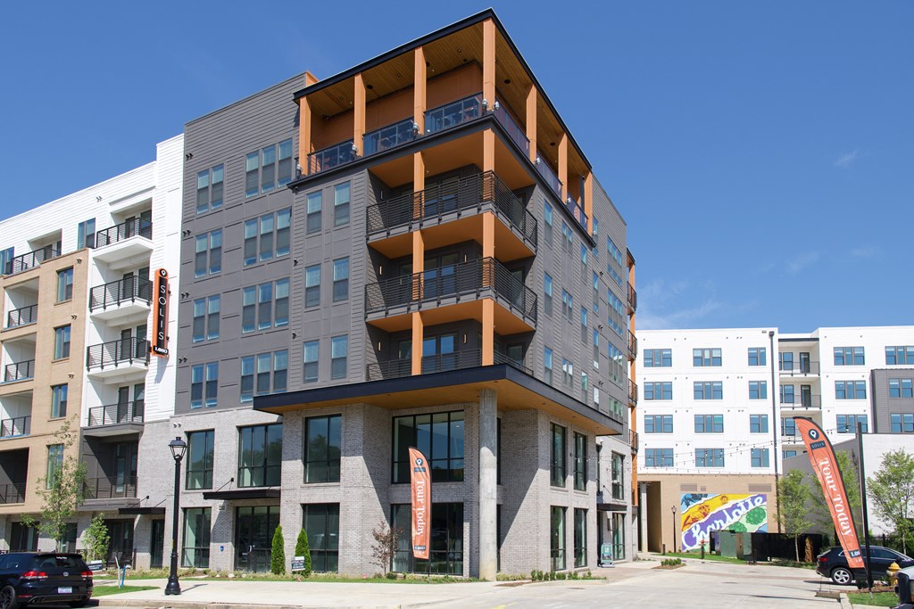 A modern multi-story building with balconies and flags in front.