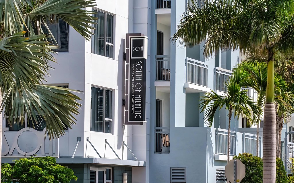 South of Atlantic Apartment Entrance Framed by Palm Trees and Custom Sign