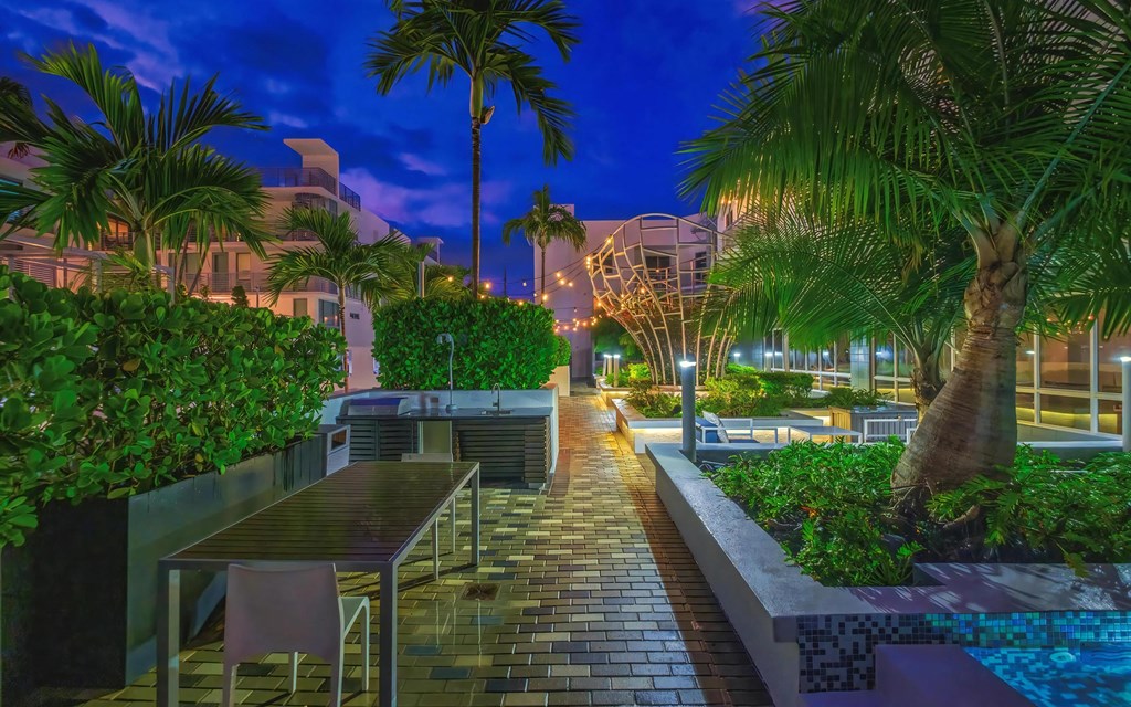 Palm-Lined Courtyard with Outdoor Kitchen and Dining Area at South of Atlantic