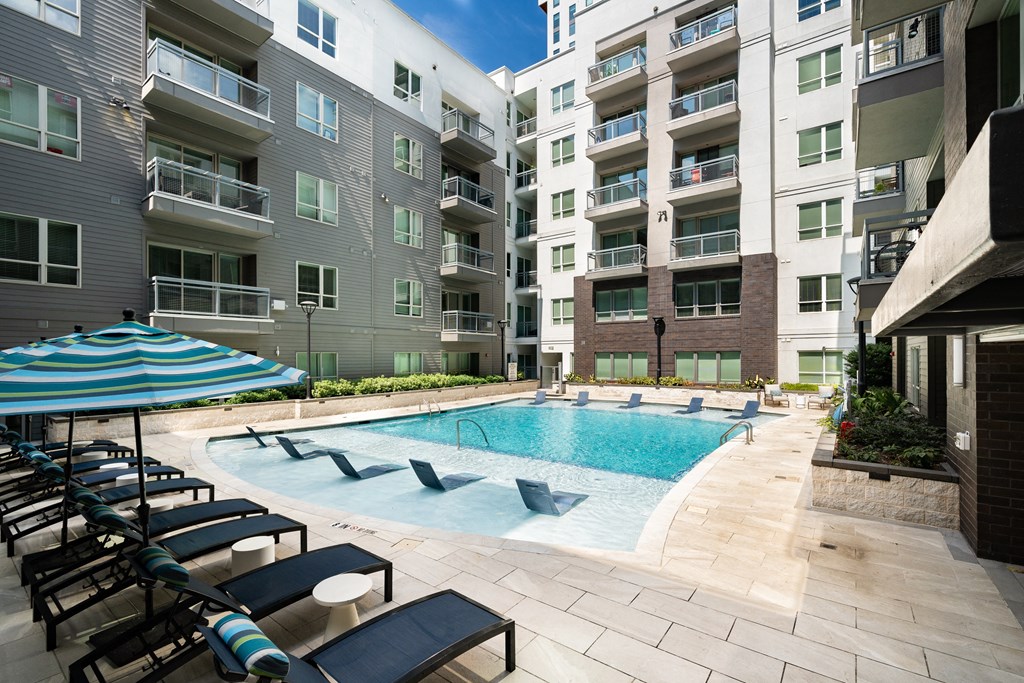 Poolside Seating and In-Water Loungers Framed by Multi-Level Apartment Building