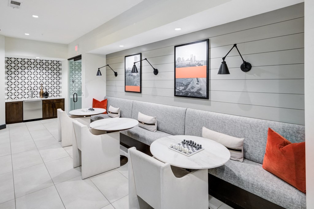 a seating area with white tables and chairs and a gray couch