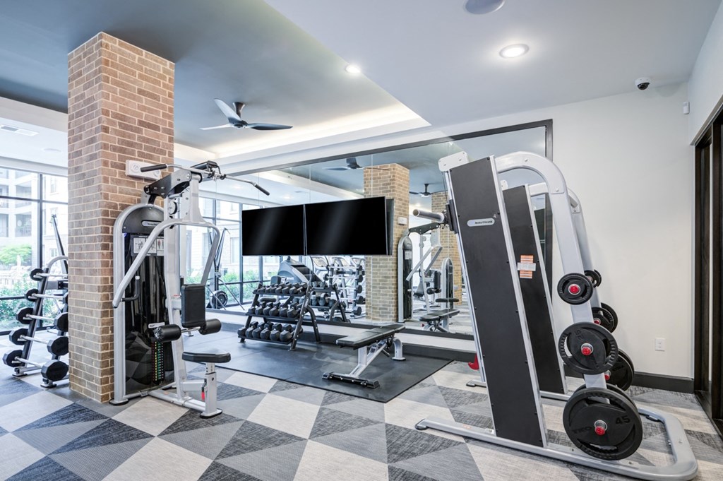 a gym with weights and a tv on the wall